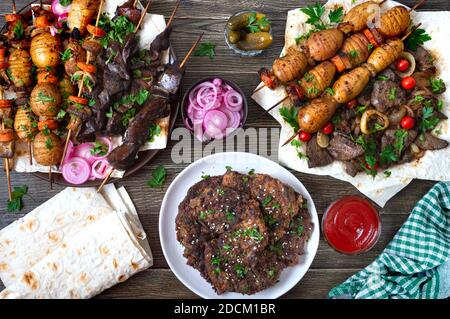 Diversi piatti di fegato kebab. Fegato spiedato, verdure intere e funghi sugli spiedini. Menu del ristorante Grill. Cucina georgiana e asiatica. Disposizione piatta. Foto Stock