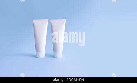 Mockup di due tubi cosmetici bianchi schiacciati su sfondo blu. Eco biologico naturale cosmetico mock-up per marcare a caldo. Foto Stock