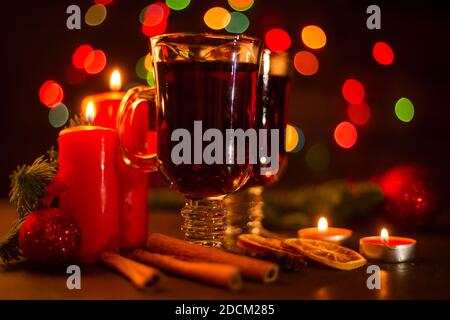 VIN brulé con bastoncini di cannella, candele d'arancia, ramo di abete e baubles sopra natale sfondo luci Foto Stock