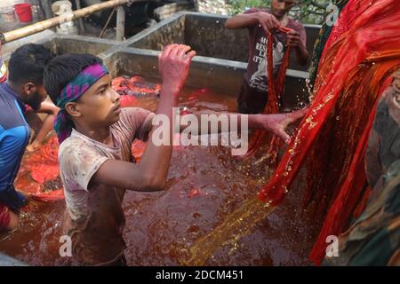 I lavoratori del Bangladesh raccolgono i tessuti dopo averli asciugati sotto il sole in una fabbrica di tintura a Narayanganj, Bangladesh. Nazmul Islam/Alamy foto d'archivio Foto Stock