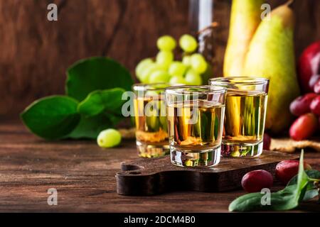 Rakija, raki o rakia - bevanda alcolica balcanica forte brandy tipo a base di frutta fermentata, tavola di legno d'annata, ancora vita in stile rustico, luogo f Foto Stock