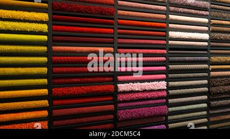 Campioni di tappeti di colori diversi su uno stand in un negozio o in una produzione. Alcuni esempi di tappeti multicolore sul pavimento Foto Stock