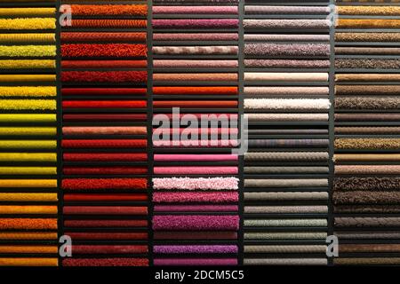 Campioni di tappeti di colori diversi su uno stand in un negozio o in una produzione. Alcuni esempi di tappeti multicolore sul pavimento Foto Stock