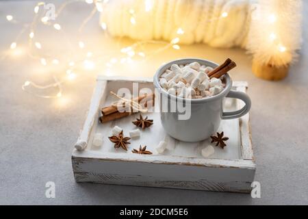 Cioccolata calda con marshmallows e spezie contro luci e decorazioni natalizie. Foto Stock