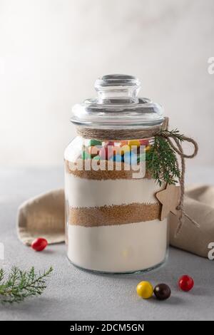 I biscotti si mescolano con caramelle colorate in vaso di vetro. Creativo regalo di Natale fai da te. Foto Stock