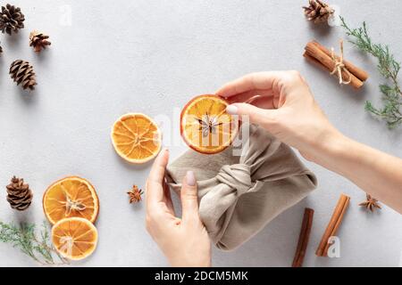 mani femminili che avvolgono i regali in tessuto di lino naturale. Confezione regalo Furoshiki giapponese Foto Stock