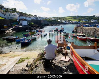 Un artista al lavoro sul porto di Coverack, Cornovaglia. Foto Stock