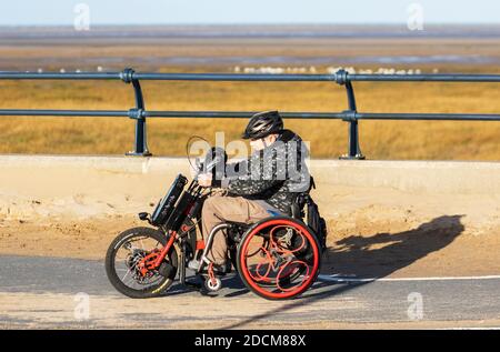 Southport, Merseyside Regno Unito Meteo. 23 Novembre 2020 luminoso e soleggiato giorno freddo sulla costa, in quanto residente locale in sella a un trike disabili gode del sole invernale. Credito; MediaWorldImages/AlamyLiveNews Foto Stock