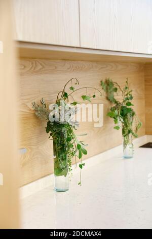 Due vasi di vetro con splendidi fiori sugli armadi della cucina Foto Stock