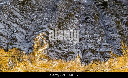 Vista dal basso del crinale di montagna con pendio coperto d'erba su un lato e scogliera a picco sull'altro. Foto Stock