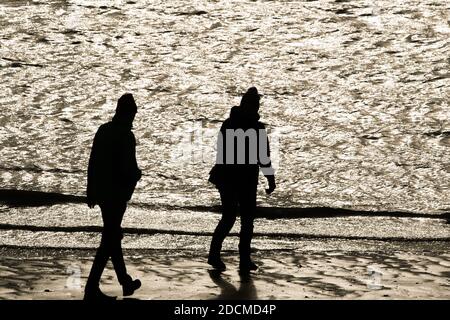 Wilhelmshaven, Germania. 22 novembre 2020. Due persone vanno per una passeggiata sulla spiaggia sud. Credit: Mohssen Assanimoghaddam/dpa/Alamy Live News Foto Stock