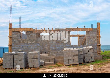 Fasi di costruzione. Casa in legno di legno con elementi sporgenti, piano terra. Materiale da costruzione impilato su pallet. Foto Stock