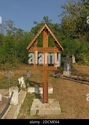 Gravetombs di pietra e croce di woorden su un cimitero s nella campagna rumena. Foto Stock