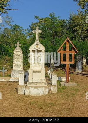 Gravetombs di pietra e croce di woorden su un cimitero s nella campagna rumena. Foto Stock