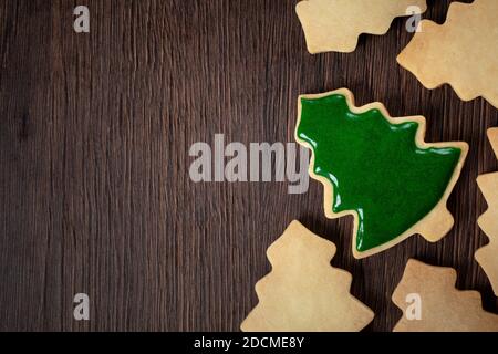 Vista dall'alto del biscotto decorato con pan di zenzero e sapore verde piano sull'albero di Natale sullo sfondo del tavolo di legno con spazio per la copia, concetto di festa. Foto Stock