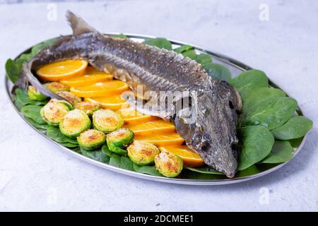 Sterlet al forno (storione) con spinaci, arance e germogli di Bruxelles. Cucina russa. Primo piano. Foto Stock