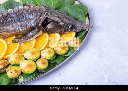 Sterlet al forno (storione) con spinaci, arance e germogli di Bruxelles. Cucina russa. Primo piano. Foto Stock