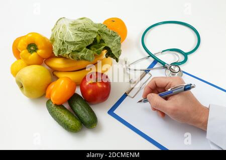 Medico nutrizionista che scrive il programma di dieta sul tavolo. Concetto giusto di alimentazione e dimagrimento Foto Stock