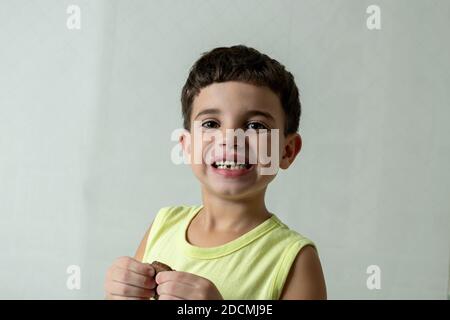 Bambino in quarantena, mangiando biscotti e fiddling con la sua tavoletta. Foto Stock