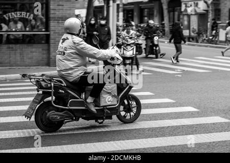 Un ragazzo di consegna Meituano su uno scooter con una borsa di consegna Eleme all'incrocio tra Jiaozhou e Wuding Road nel distretto Jing'an di Shanghai. Foto Stock