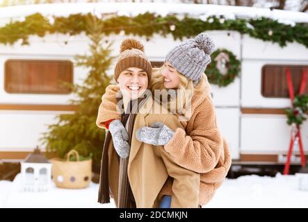 Giovane coppia romantica che si diverte al campeggio invernale, giocando e ridendo insieme Foto Stock