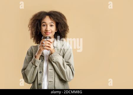 Bevanda calda e pausa preferite. Felice millennial curly donna afroamericana in casual, inalando profumo di caffè Foto Stock