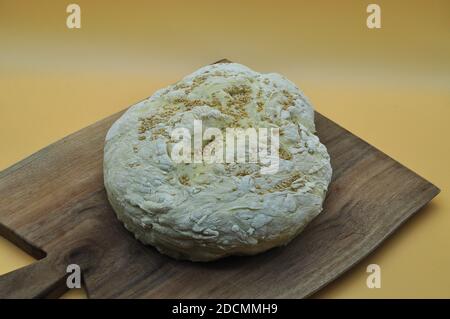 composizione di un pane fatto a mano appena sfornato posto su un elegante tagliere in legno Foto Stock