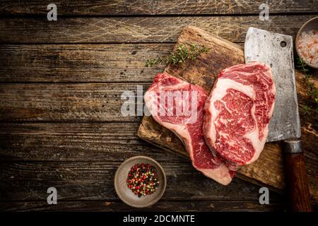 Varietà di bistecche fresche di carne prime all'Angus Black, New York, Ribeye e stagionatura su sfondo di legno, vista dall'alto Foto Stock
