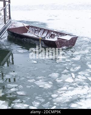 Piccola barca da pesca intrappolata nel ghiaccio sul fiume Danubio ghiacciato Foto Stock