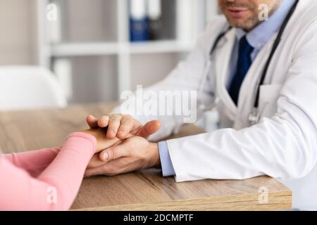 Primo piano di un medico maschile che tiene le mani di una paziente femminile Foto Stock