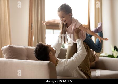 Padre alza il piccolo adorabile bambino divertendosi insieme indoor Foto Stock