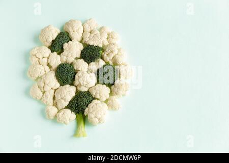 Pezzi di broccoli e cavolfiore sotto forma di A. albero piatto posare su uno sfondo di cemento blu con copia spazio Foto Stock