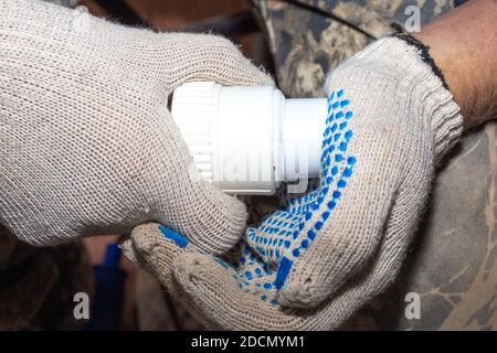 incollaggio di parti di un tubo dell'acqua in pvc mediante riscaldamento, montaggio e installazione di impianti idraulici. Foto Stock