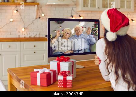 Giovane donna videochiama i suoi genitori anziani nelle vacanze di Natale in blocco Foto Stock