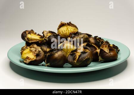 Castagne cotte al fuoco in un piatto Foto Stock