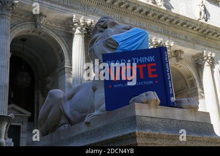 Lion di fronte alla New York Public Library indossare la maschera, tenendo un libro 'leggere, pensare voto' Foto Stock