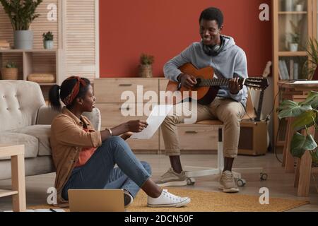 Ritratto di due giovani musicisti afroamericani che suonano la chitarra e scrivere musica insieme in uno studio di registrazione domestico Foto Stock