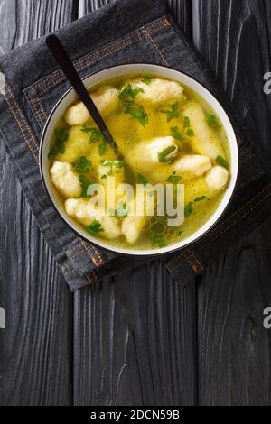 Zuppa di semola Dumpling Griessnockerlsuppe molto deliziosi sono questi gnocchi in zuppa di verdure chiaro primo piano in un piatto sul tavolo. Verticale superiore vi Foto Stock