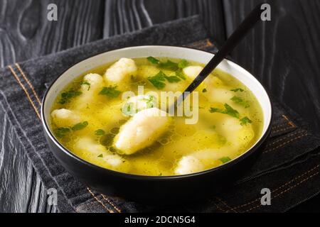 Gnocchi di semola fatti in casa in brodo di carne primo piano in un piatto sulla tavola. Orizzontale Foto Stock