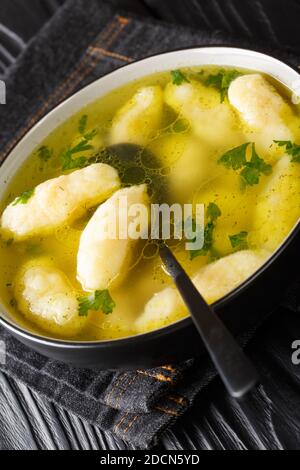 Zuppa limpida con gnocchi di semola in primo piano in un piatto sul tavolo. Verticale Foto Stock