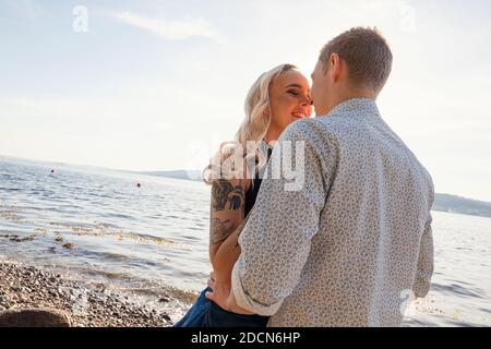 Bella giovane coppia Kissing a Beach il giorno di sole Foto Stock
