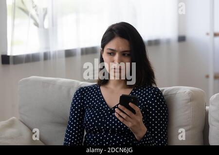 Stressato giovane donna asiatica che tiene telefono, ha ricevuto cattive notizie Foto Stock