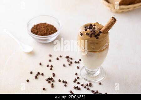 Un primo piano di un bicchiere di caffè Dalgona sul tavolo con gocce di cioccolato su di esso Foto Stock