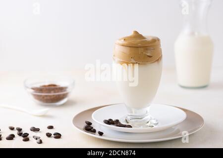 Un primo piano di un bicchiere di caffè Dalgona sul tavolo con i chicchi di caffè Foto Stock