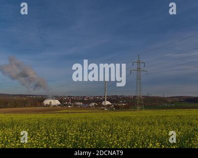 Centrale nucleare a Neckarwestheim, Germania, situata sulla riva del fiume Neckar, con linea elettrica, pilone e un fiorente campo agricolo. Foto Stock