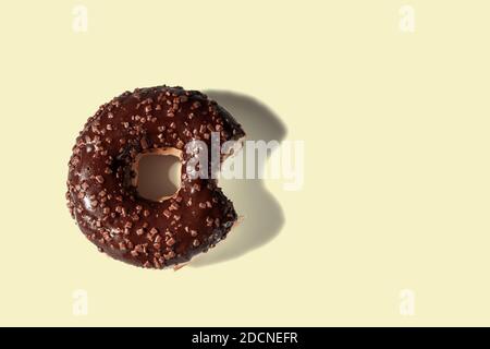 Primo piano vista della ciambella di cioccolato amaro su sfondo giallo isolato. Concetto di cibo e salute. Foto Stock