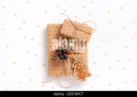 Due scatole regalo avvolte in carta artigianale con decorazioni su sfondo bianco decorato con confetti Foto Stock