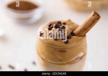 Un primo piano di un bicchiere di caffè Dalgona al cioccolato scheggia su di esso con uno sfondo sfocato Foto Stock