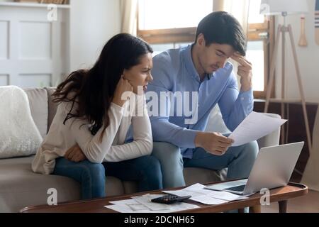 Giovane coppia sposata interessata che studia lettere bancarie informando sul debito Foto Stock