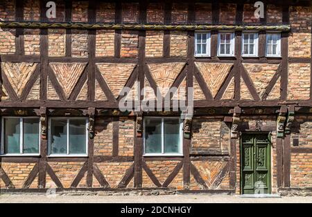 Facciata di una storica casa a graticcio con mattoni in vari motivi, ornamenti scolpiti, e una porta verde a Ystad, Svezia. Foto Stock